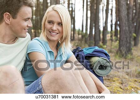 Stock Image - Hiking couple looking at each other while relaxing in forest. Fotosearch