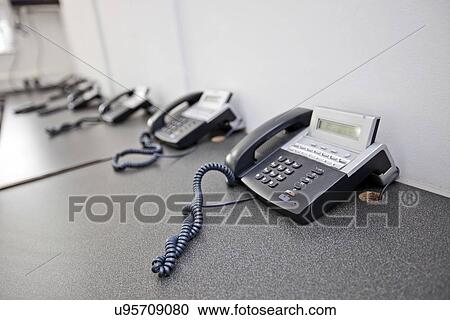 Stock Image - Landline telephones on desk in television station. Fotosearch