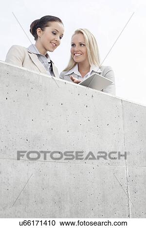 Low angle view of smiling business executives using digital tablet on office terrace against sky View Large Photo Image Stock Image - Low angle view of smiling business executives using digital tablet on office terrace against sky. Fotosearch