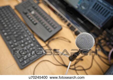 Stock Image - Microphone and computer keyboards on table at television studio. Fotosearch