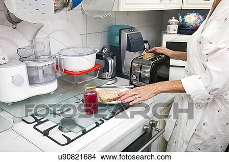 Midsection of senior woman preparing toast at kitchen counter View Large Photo Image Picture - Midsection of senior woman preparing toast at kitchen counter. Fotosearch