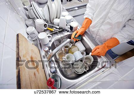 Stock Photo - Midsection of woman washing utensil at kitchen sink. Fotosearch