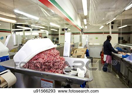 Stock Image - Minced meat in container with employee standing in background at store. Fotosearch
