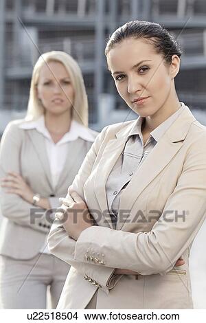 Picture - Portrait of confident young businesswomen standing arms crossed outdoors. Fotosearch