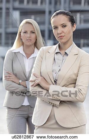 Stock Photo - Portrait of confident young businesswomen standing arms crossed outdoors. Fotosearch