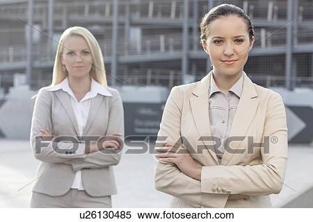 Stock Photography - Portrait of confident young businesswomen standing arms crossed outdoors. Fotosearch