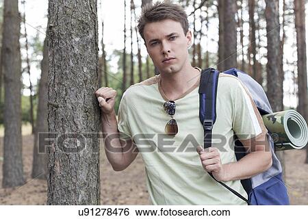 Stock Photograph - Portrait of handsome young man with backpack hiking in forest. Fotosearch