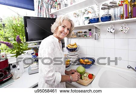 Portrait of happy senior woman chopping fresh vegetables at kitchen counter View Large Photo Image Stock Image - Portrait of happy senior woman chopping fresh vegetables at kitchen counter. Fotosearch