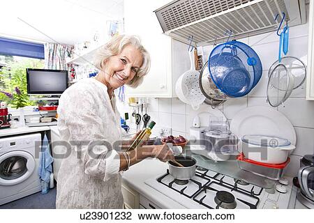 Portrait of happy senior woman preparing food in domestic kitchen View Large Photo Image Stock Image - Portrait of happy senior woman preparing food in domestic kitchen. Fotosearch
