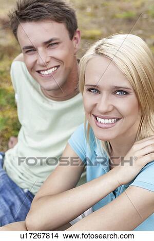 Portrait of smiling young woman with man relaxing in park View Large Photo Image Picture - Portrait of smiling young woman with man relaxing in park. Fotosearch