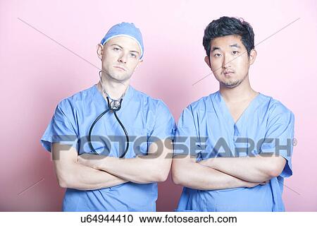 Portrait of two male surgeons standing with arms crossed over pink background View Large Photo Image Stock Image - Portrait of two male surgeons standing with arms crossed over pink background. Fotosearch