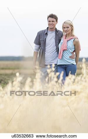 Portrait of young couple standing at field View Large Photo Image Stock Image - Portrait of young couple standing at field. Fotosearch