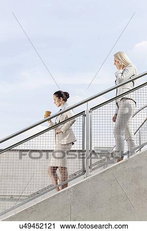 Profile shot of businesswomen moving down stairs together against sky View Large Photo Image Stock Image - Profile shot of businesswomen moving down stairs together against sky. Fotosearch