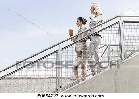 Profile shot of businesswomen moving down stairs against sky View Large Photo Image Stock Image - Profile shot of businesswomen moving down stairs against sky. Fotosearch