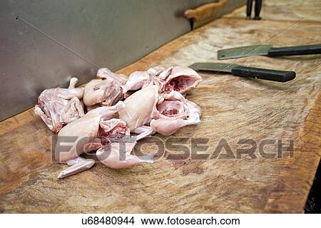 Picture - Raw chicken pieces and butcher knife on cutting board in store. Fotosearch