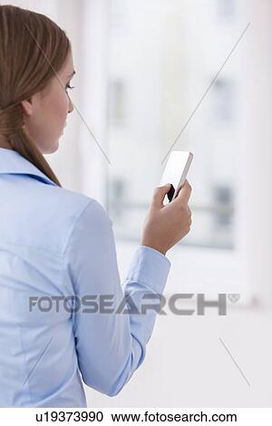 Rear View of a Woman holding a smart phone View Large Photo Image Stock Image - Rear View of a Woman holding a smart phone. Fotosearch