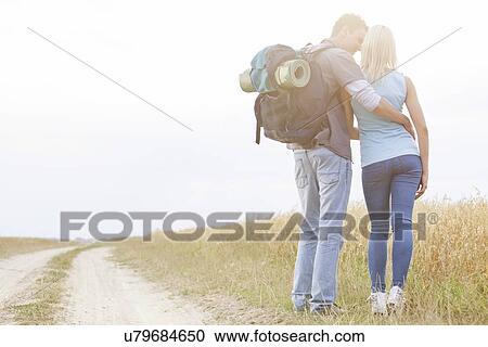 Rear view of loving hiking couple standing together at field View Large Photo Image Stock Image - Rear view of loving hiking couple standing together at field. Fotosearch
