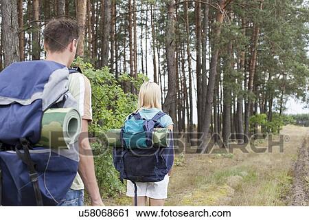 Rear view of young backpackers walking in forest trail View Large Photo Image Stock Image - Rear view of young backpackers walking in forest trail. Fotosearch