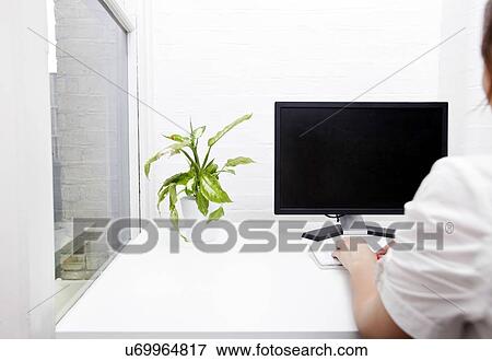 Stock Photo - Rear view of young businesswoman using computer at desk. Fotosearch