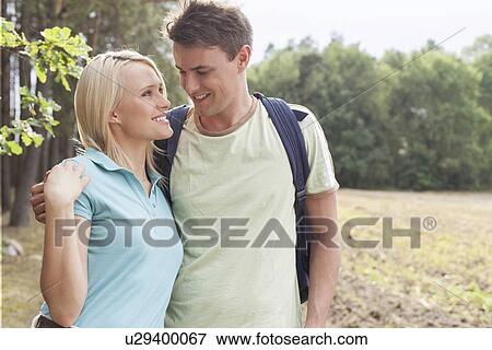 Romantic young couple looking at each other while hiking in forest View Large Photo Image Stock Photo - Romantic young couple looking at each other while hiking in forest. Fotosearch