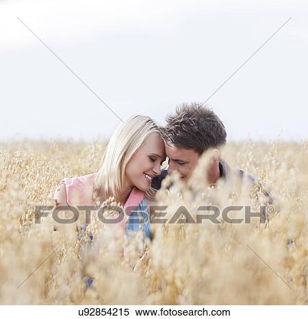 Stock Photography - Romantic young couple sitting amidst field. Fotosearch