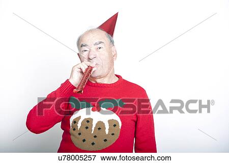 Senior adult man wearing Christmas jumper blowing party blower View Large Photo Image Stock Photo - Senior adult man wearing Christmas jumper blowing party blower. Fotosearch