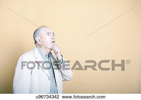 Senior adult man with his hand on his chin looking up inquisitively View Large Photo Image Stock Image - Senior adult man with his hand on his chin looking up inquisitively . Fotosearch