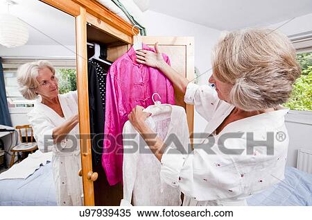 Senior woman choosing dress from closet at home View Large Photo Image Stock Photography - Senior woman choosing dress from closet at home. Fotosearch