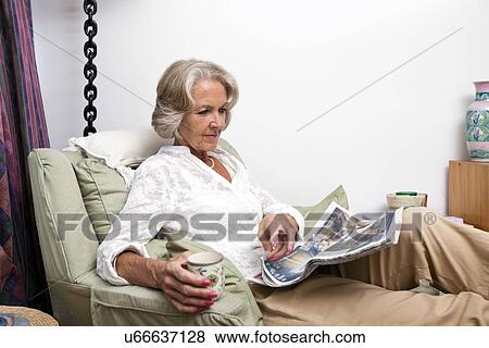 Senior woman reading newspaper while relaxing at home View Large Photo Image Stock Photo - Senior woman reading newspaper while relaxing at home. Fotosearch