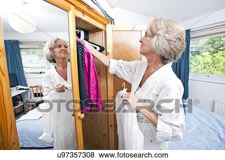 Senior woman selecting dress from closet at home View Large Photo Image Stock Photo - Senior woman selecting dress from closet at home. Fotosearch