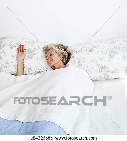 Stock Photography - Senior woman sleeping in bed at home. Fotosearch