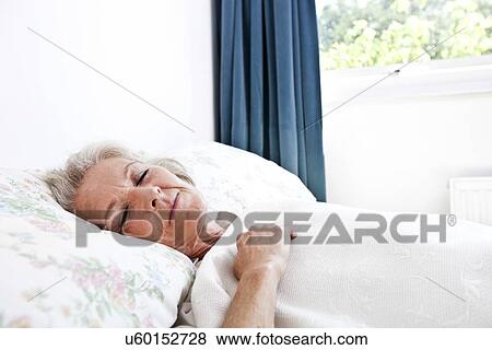 Stock Photo - Senior woman sleeping in bedroom at home. Fotosearch