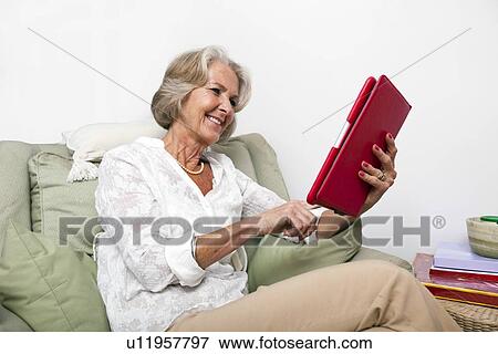Senior woman using digital tablet on armchair at home View Large Photo Image Stock Photo - Senior woman using digital tablet on armchair at home. Fotosearch