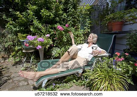 Senior woman with wineglass relaxing on lounge chair in garden View Large Photo Image Stock Image - Senior woman with wineglass relaxing on lounge chair in garden. Fotosearch
