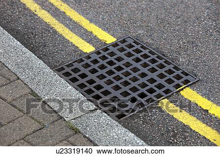 Stock Image - Street drain over Double yellow line on street. Fotosearch