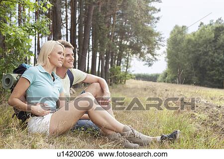 Thoughtful hiking couple looking away while relaxing in forest View Large Photo Image Stock Photograph - Thoughtful hiking couple looking away while relaxing in forest. Fotosearch