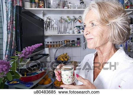 Thoughtful senior woman looking away while holding coffee cup in kitchen View Large Photo Image Stock Photography - Thoughtful senior woman looking away while holding coffee cup in kitchen. Fotosearch