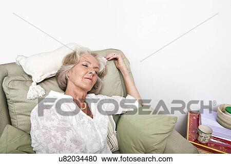 Stock Image - Tired senior woman sleeping on armchair at home. Fotosearch
