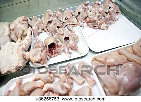 Stock Image - Variety of raw chicken pieces in tray at store. Fotosearch