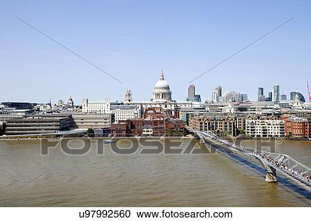 Stock Image - View of Millennium Bridge with view of City of London in the Background. Fotosearch