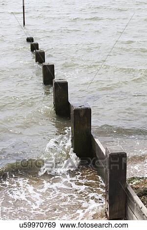 Stock Photo - Wave hitting beach Groyne. Fotosearch