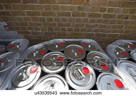 Stock Image - Wrapped tins against brick wall at warehouse. Fotosearch