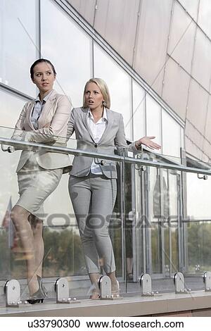 Stock Image - Young businesswoman arguing with female colleague at office balcony. Fotosearch