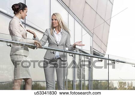 Stock Image - Young businesswoman arguing with female colleague at office balcony. Fotosearch