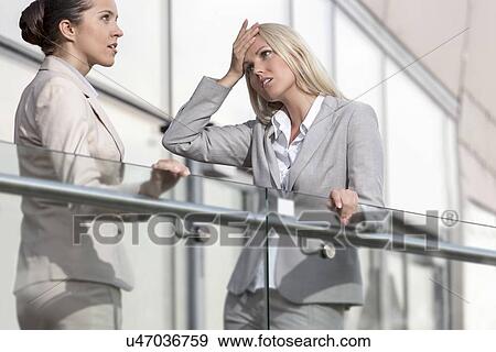 Young businesswoman arguing with female colleague at office railing View Large Photo Image Stock Photo - Young businesswoman arguing with female colleague at office railing. Fotosearch