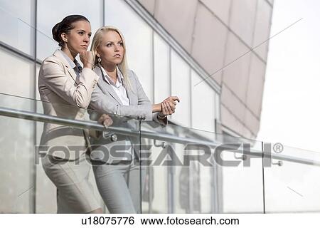 Young businesswomen on office railing looking away View Large Photo Image Stock Photograph - Young businesswomen on office railing looking away. Fotosearch