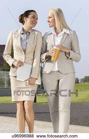 Young businesswomen with disposable cup and laptop walking on street View Large Photo Image Stock Photo - Young businesswomen with disposable cup and laptop walking on street. Fotosearch