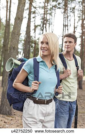 Stock Image - Young couple with backpacks trekking in forest. Fotosearch