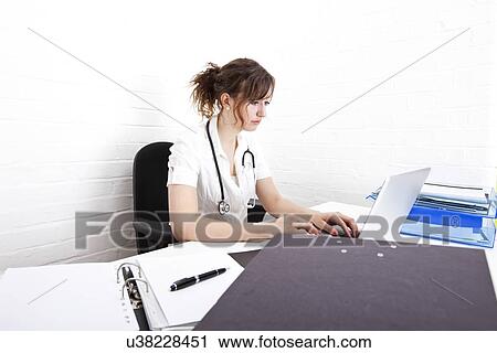 Young female doctor using laptop at desk in clinic View Large Photo Image Stock Image - Young female doctor using laptop at desk in clinic. Fotosearch