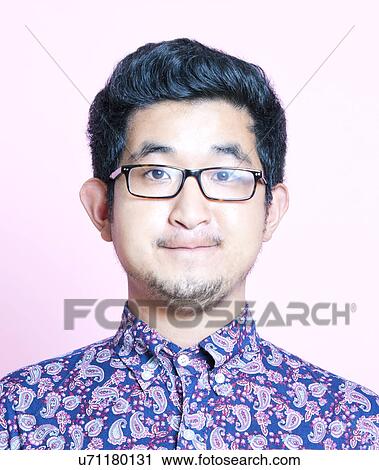 Stock Image - Young Geeky Asian Man in colorful shirt wearing glasses. Fotosearch